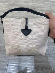 Close-up of contrast canvas bucket bag with heart leather patch and black handles