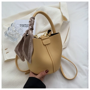 Sac seau jaune grainé avec foulard en soie et bandoulière amovible sur fond décoratif
