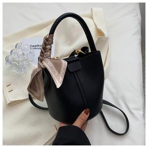 Détail du sac seau en cuir grainé noir avec poignée en foulard de soie et détails dorés