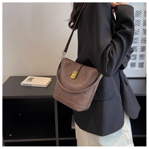 Brown vintage leather bucket bag with gold twist lock shown on a female model