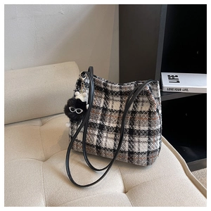 Macro shot of plaid canvas tote with leather handles and cute plush charm on a sofa
