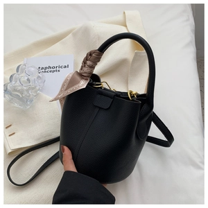 Détail du sac seau en cuir grainé noir avec foulard en soie décoratif sur l'anse