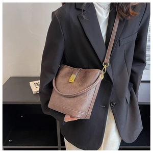 Detailed macro view of dark brown bucket bag with lychee texture and gold buckle
