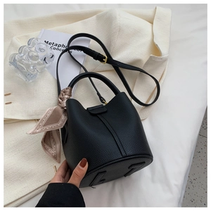 Détail du sac seau en cuir grainé noir avec foulard en soie décoratif sur l'anse