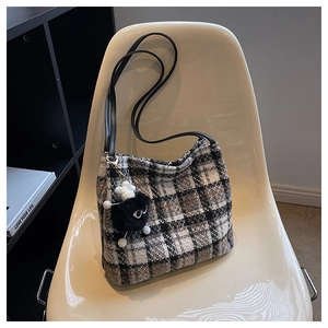 Detail of tweed checkered tote bag with leather strap and black pom-pom charm