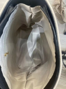 Close-up of tote bag interior with gray herringbone lining and a gold zipper pocket