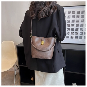 Detail of vintage brown leather bucket bag with brass buckle on a shoulder model