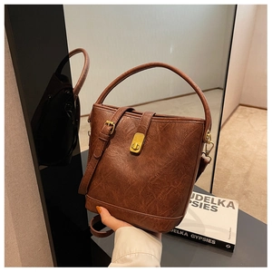 Detail of vintage brown bucket bag showing pleated leather texture and gold buckle