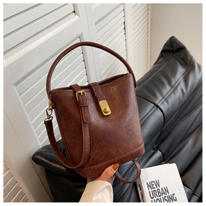 Close-up of vintage brown leather bucket bag with gold metal buckle and textured finish