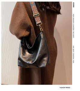 Detail view of black hobo bag featuring ethnic pattern wide strap and golden hardware