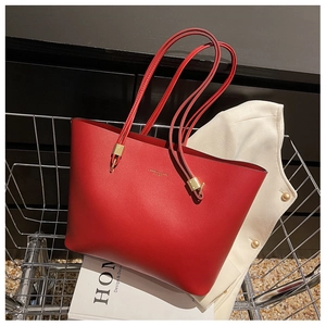 Close-up of red leather tote bag with gold lettering placed in a metal shopping cart