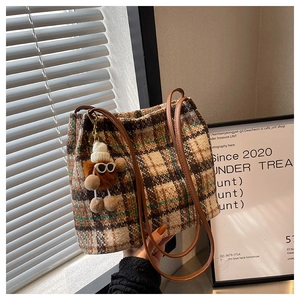 Detail of tweed tote bag with classic plaid pattern and small plush charm accessory