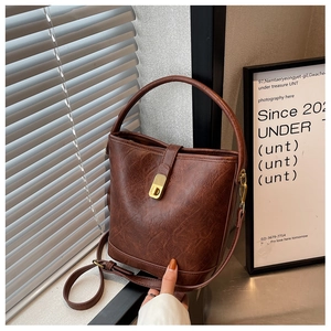 Detail of vintage brown bucket bag with wrinkled leather texture and golden metal twist lock