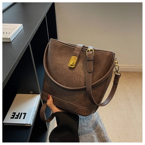 Detailed shot of dark brown leather bucket bag with retro texture and gold twist lock