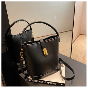 Detail of vintage black embossed leather bucket bag with gold clasp and mirror reflection