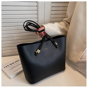 Close-up of black leather tote bag with gold lettering logo and durable metallic buckles