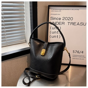 Close-up of black leather bucket bag with gold twist lock and elegant studio lighting