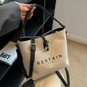 Canvas bucket bag with leather handles and horn lock closure in cream and black