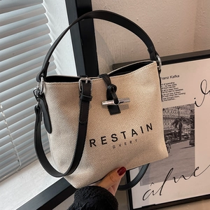 Minimalist off-white canvas bucket bag with black leather trim and top handle