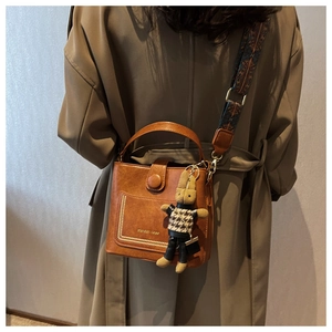 Caramel leather bucket bag detail with geometric strap and cute rabbit pendant