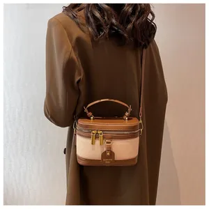 Détail d'un mini sac en toile avec garniture en cuir marron porté par un mannequin