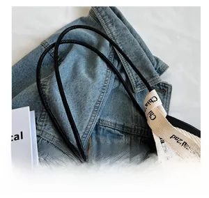 Detail showing white pleated fabric texture with black thin leather straps and printed ribbon