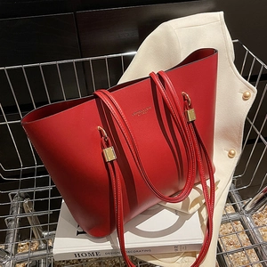Red leather tote bag with large capacity and gold hardware in a stylish home setting