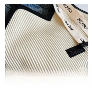 Detail of white pleated fabric texture with black leather trim and logo webbing strap