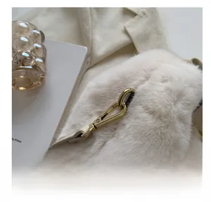 Close-up of premium gold hardware hook on a soft off-white plush faux fur handbag