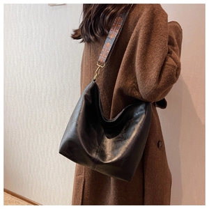 Detail of black soft leather hobo bag with vintage stitching and colorful woven strap