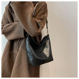 Detail of black hobo bag with vintage texture and stylish ethnic patterned strap