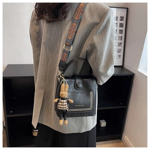 Detail of black pebbled leather bucket bag with jacquard strap and rabbit charm