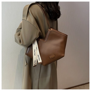 Detail of dark brown tote bag with vertical stripes and beige woven logo strap