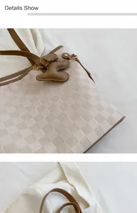 Nahaufnahme der Schachbrett-Textur und braunen Ledergriffe einer Tragetasche