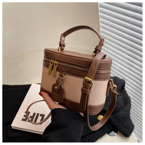 Détail du sac boîte vintage avec bordures en cuir brun, toile et fermetures éclair dorées