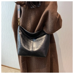 Close-up of black oversized tote bag with textured leather and ethnic jacquard strap