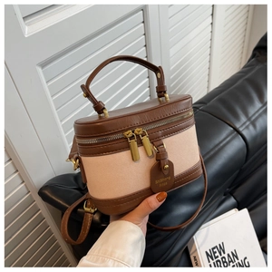 Détail du mini sac seau en toile et cuir marron avec étiquette de marque et poignée
