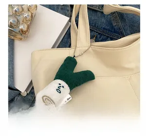 Close-up of green and white scallion plush pendant on canvas tote bag with metal chain