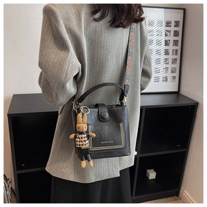 Detail of black bucket bag featuring jacquard strap and cute rabbit pendant charm