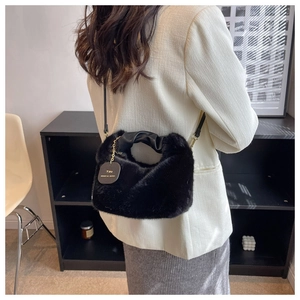 Detail of plush black faux fur handbag with knotted leather handle and heart tag