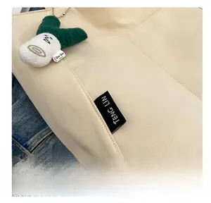 Detail view of canvas tote bag featuring branded woven label and plush onion charm attachment