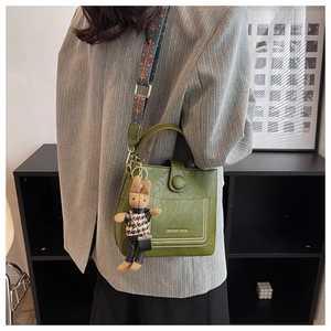 Detail of dark green leather bucket bag with rivet decor and woven ethnic style strap