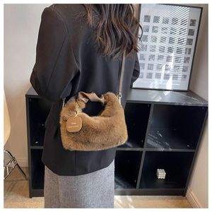 Model wearing a brown faux fur handbag with leather knot handle and gold slogan tag