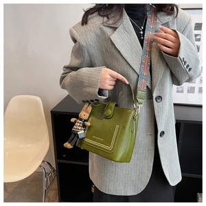 Close-up of green lychee textured crossbody bag with ethnic strap and rabbit charm