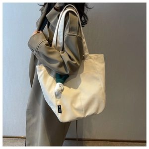 Cream canvas tote bag detail featuring a convenient front pocket and cute green charm
