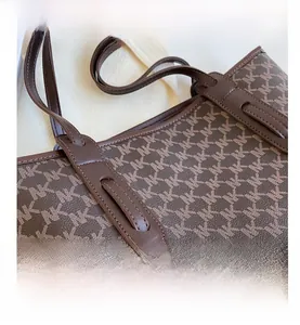 Close-up of coffee brown leather tote bag with monogram print and durable handle stitching