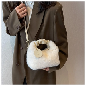 Detail of white faux fur handbag with cream leather handles and branded square tag