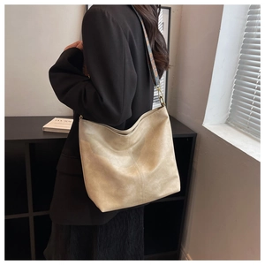 Detail of cream bucket bag with ethnic embroidery strap and gold metallic hardware