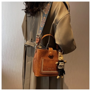 Detail of vintage brown leather bucket bag with ethnic woven strap and rabbit charm