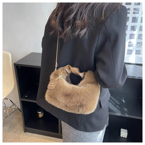 Close-up of brown faux fur bag with a leather twisted handle and engraved tag detail